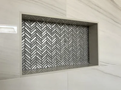Shower niche with herringbone glass mosaic backing