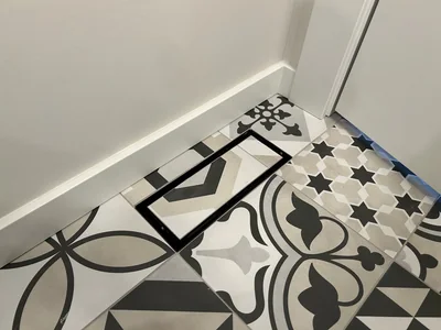 Flush-set floor vent in patterned encaustic tile