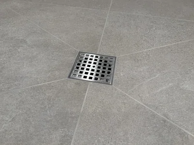UberTile stainless steel shower drain set flush and centred in a large-format tile floor